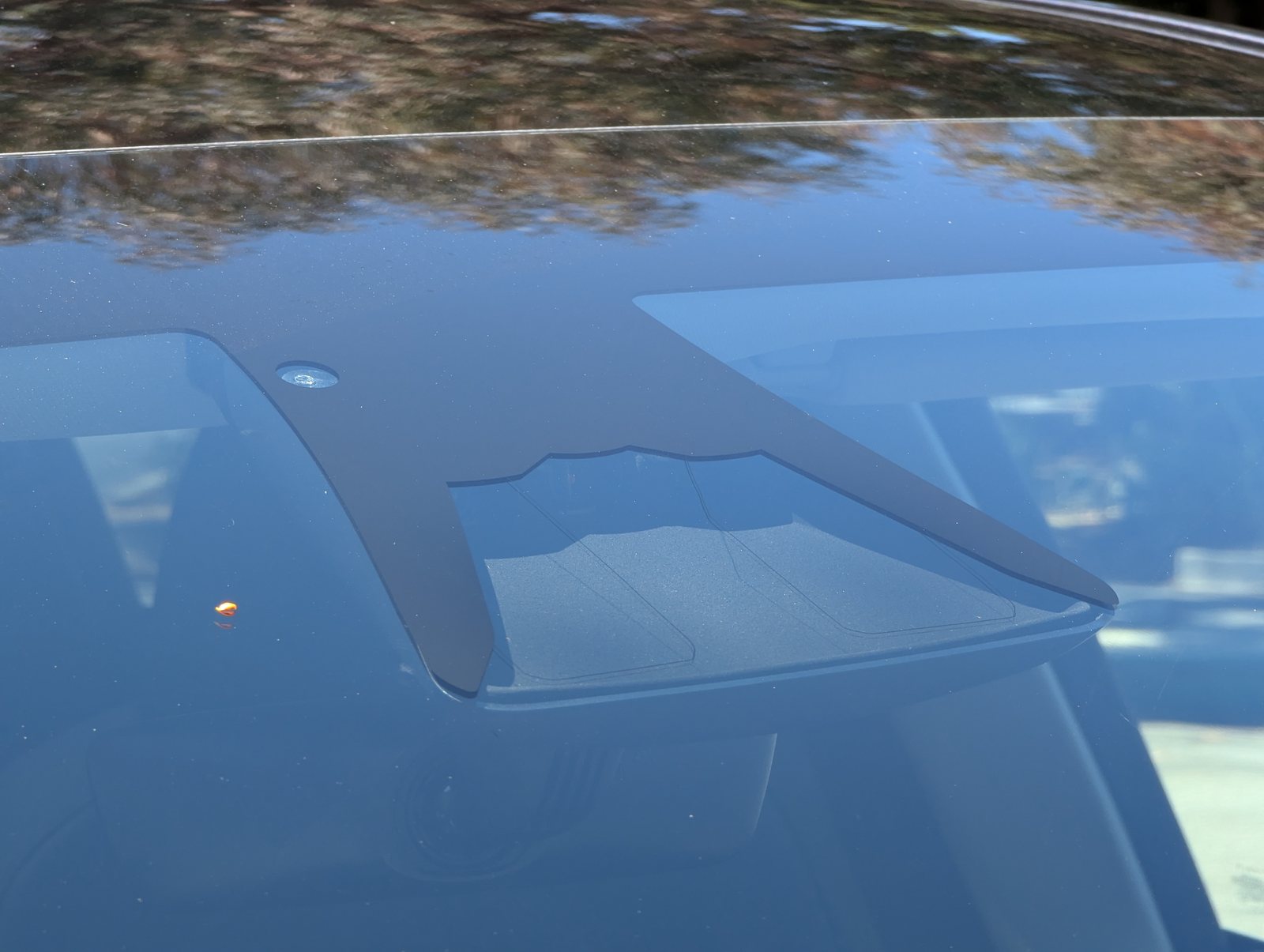 Close-up of a forward-facing driver-assistance camera system mounted behind a windshield.