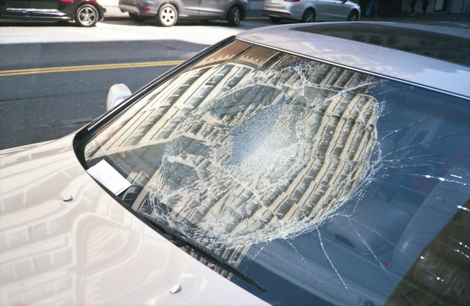 White sedan with extensive impact damage across the windshield.