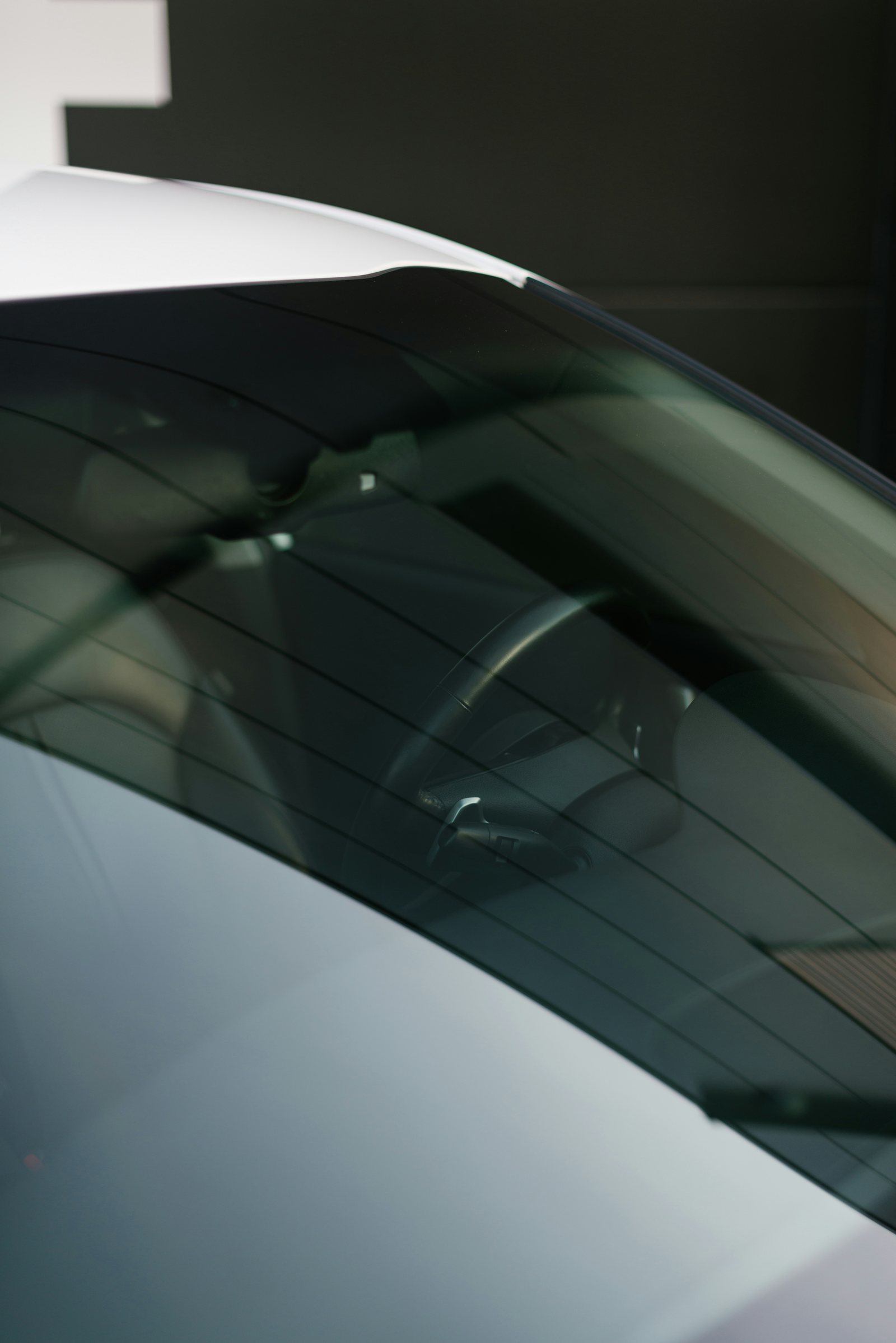 Upper section of a modern installed windshield with a camera housing near the rearview mirror.