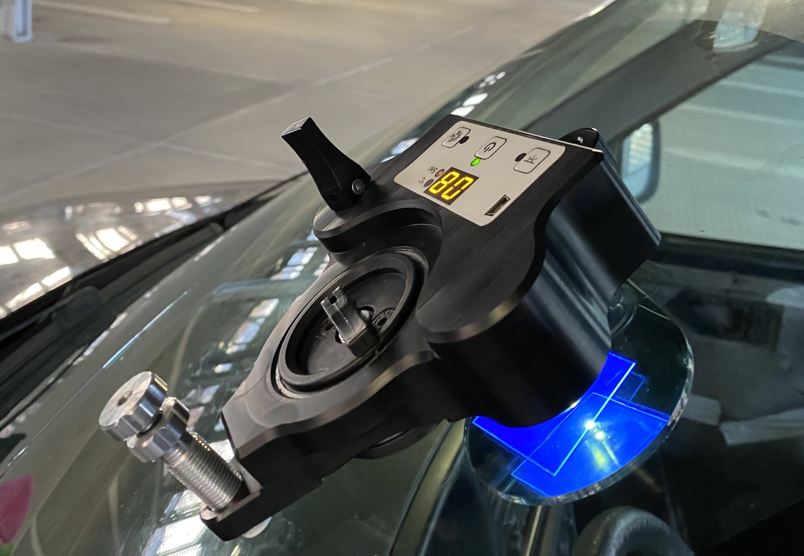 Windshield chip repair bridge and UV lamp positioned over a small stone chip.