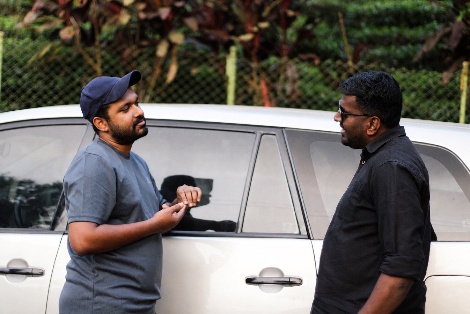 Customer and automotive service professional discussing a vehicle beside the car outdoors.