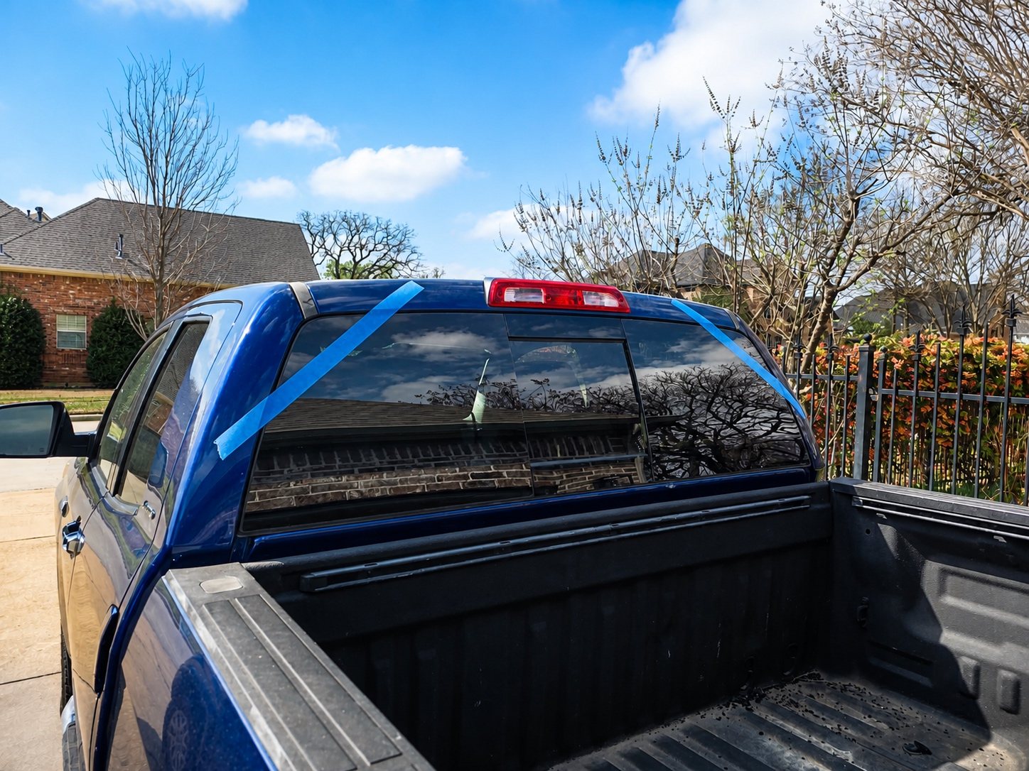 Blue pickup truck with a completed rear-window installation and retention tape.