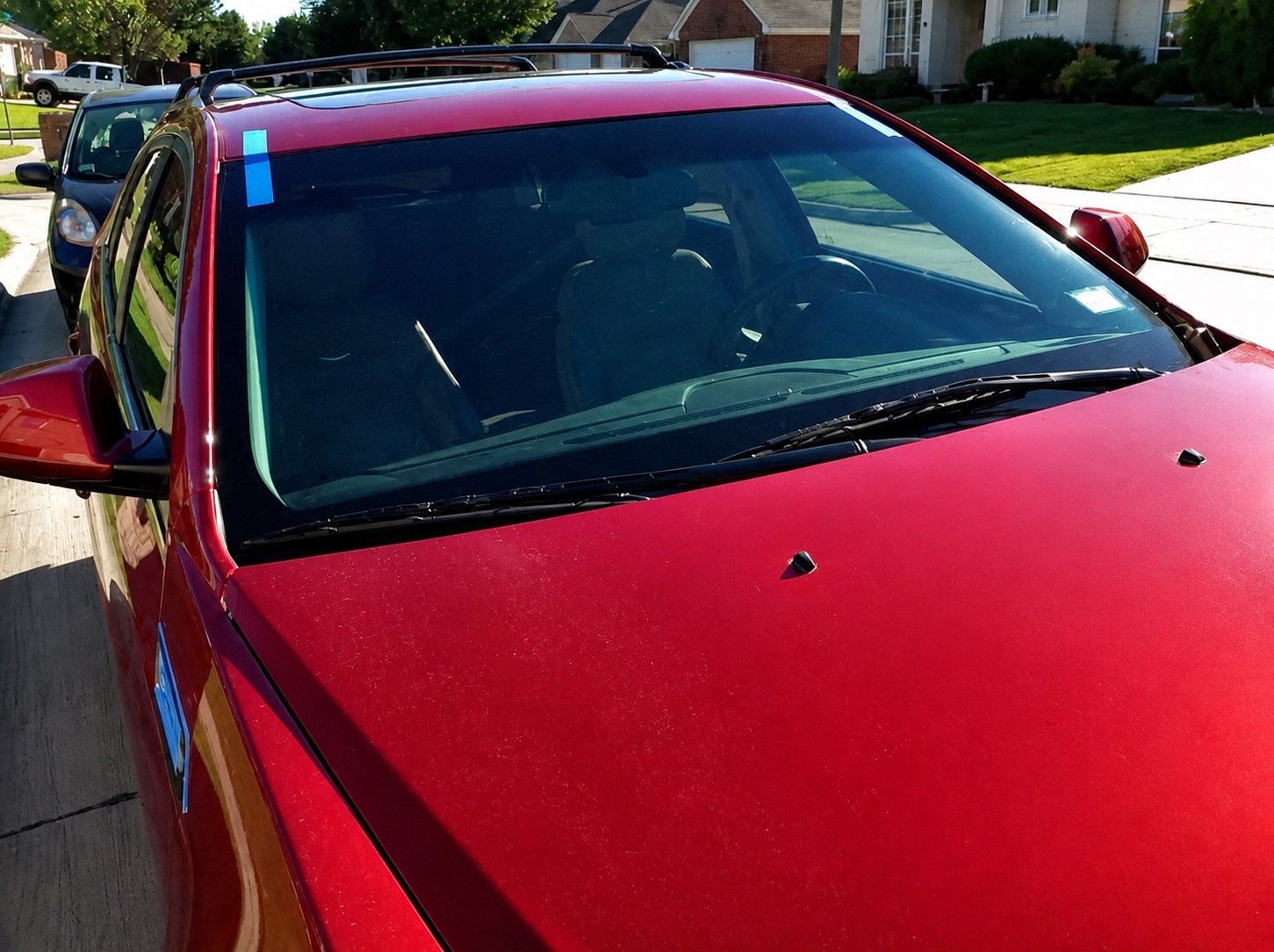Completed windshield installation on a red SUV at a residential service location.