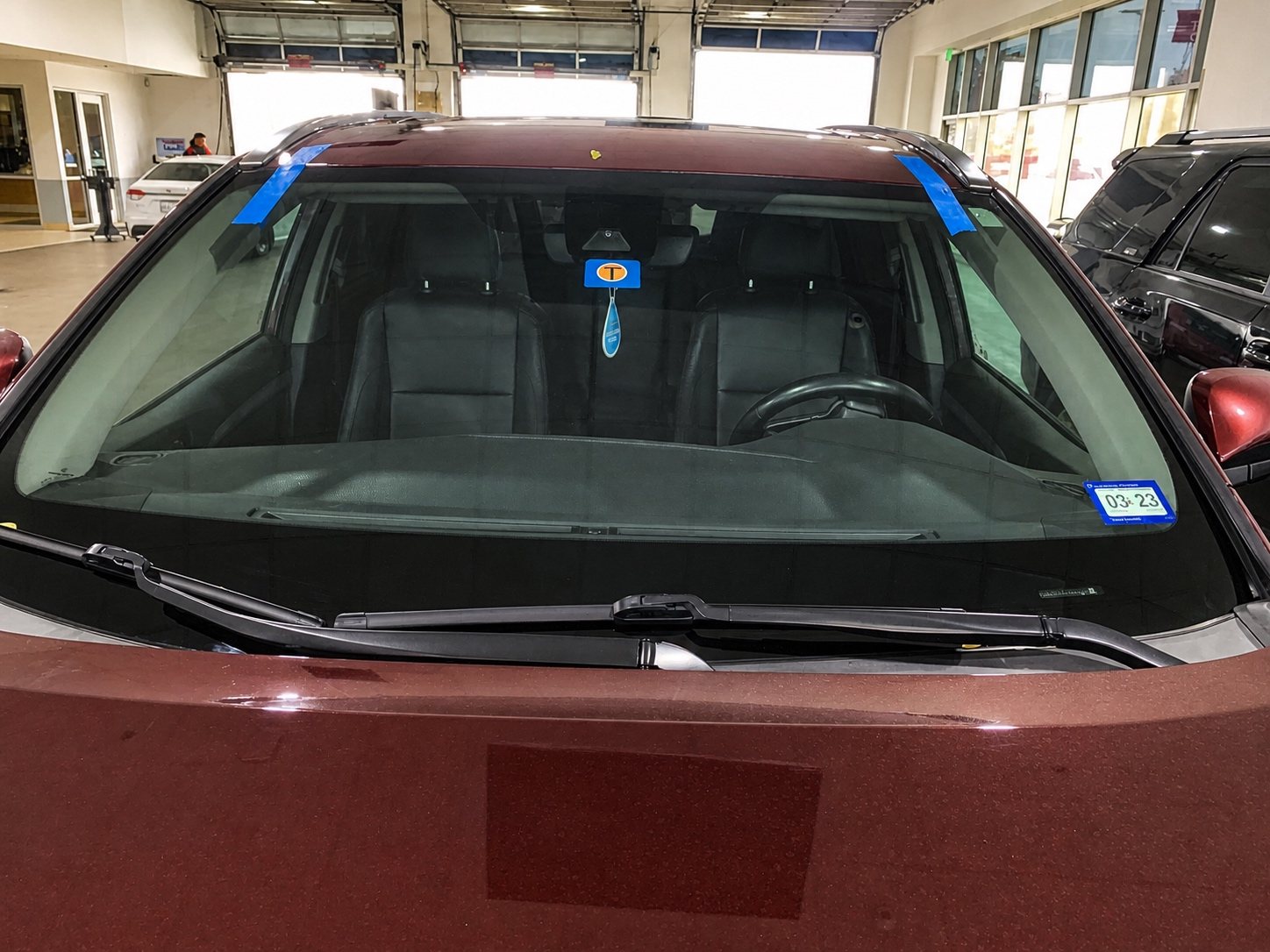 Maroon SUV after windshield installation inside a professional service bay.