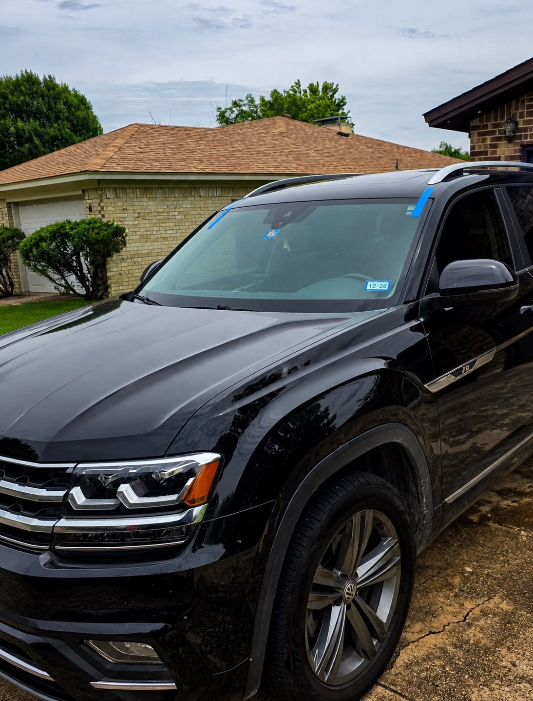 Black Volkswagen SUV after windshield installation with retention tape in place.